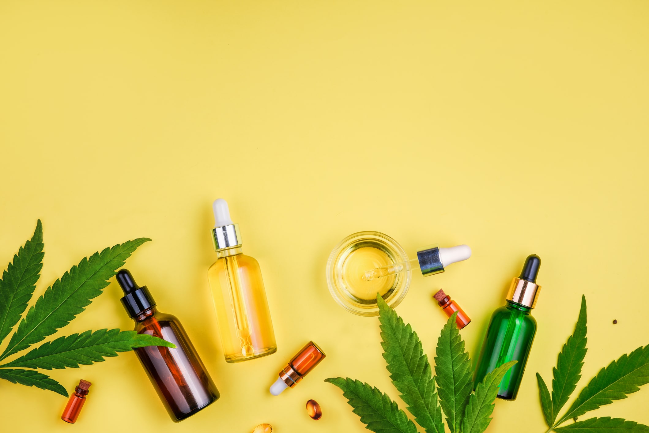 Glass bottle and dropper CBD OIL, THC tincture and cannabis leaf on background. Laboratory Production of cosmetics with CBD oil.